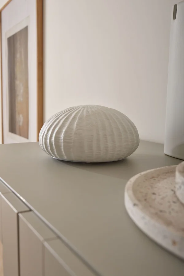 Biała dekoracja ceramiczna na beżowej komodzie.